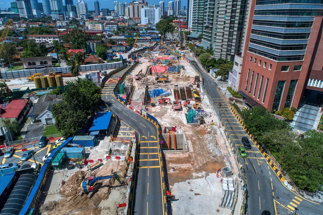 Aerial view of Raja Uda MRT Station site showing the reinforced concrete and excavation works in progress.