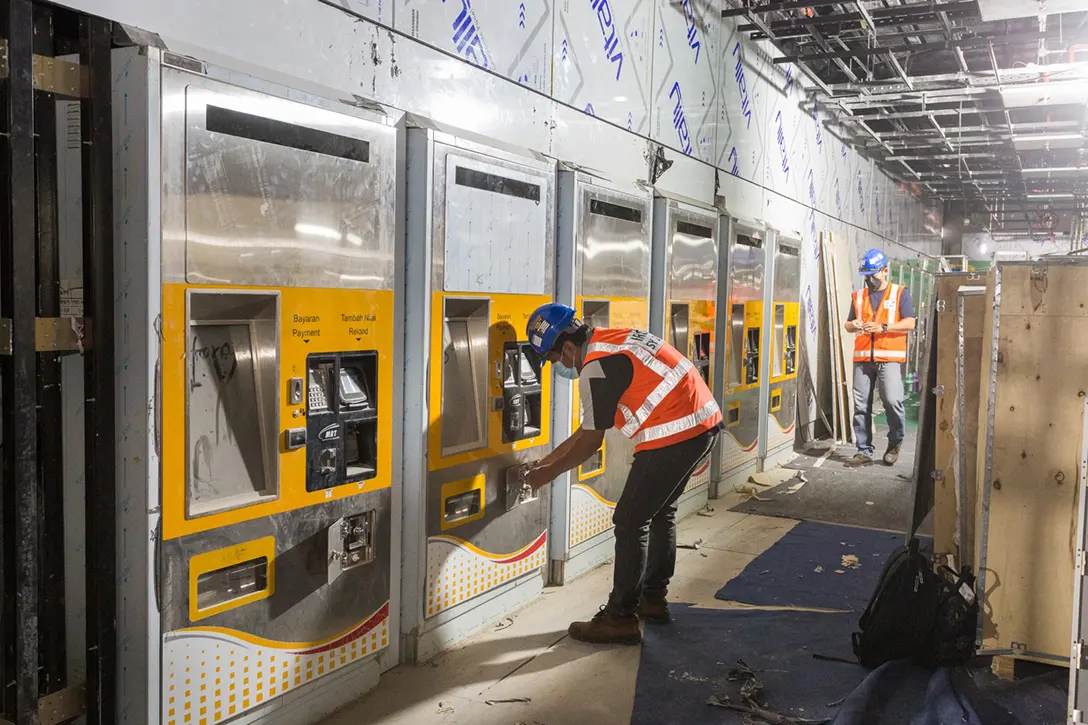 Installation of ticket vending machine accessories at Persiaran KLCC MRT Station concourse level.