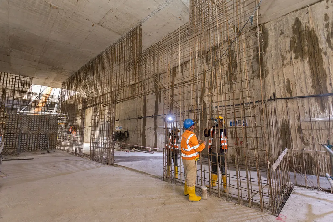 Rebar fixers completing reinforcement bars for reinforced concrete wall in Raja Uda MRT Station concourse level.