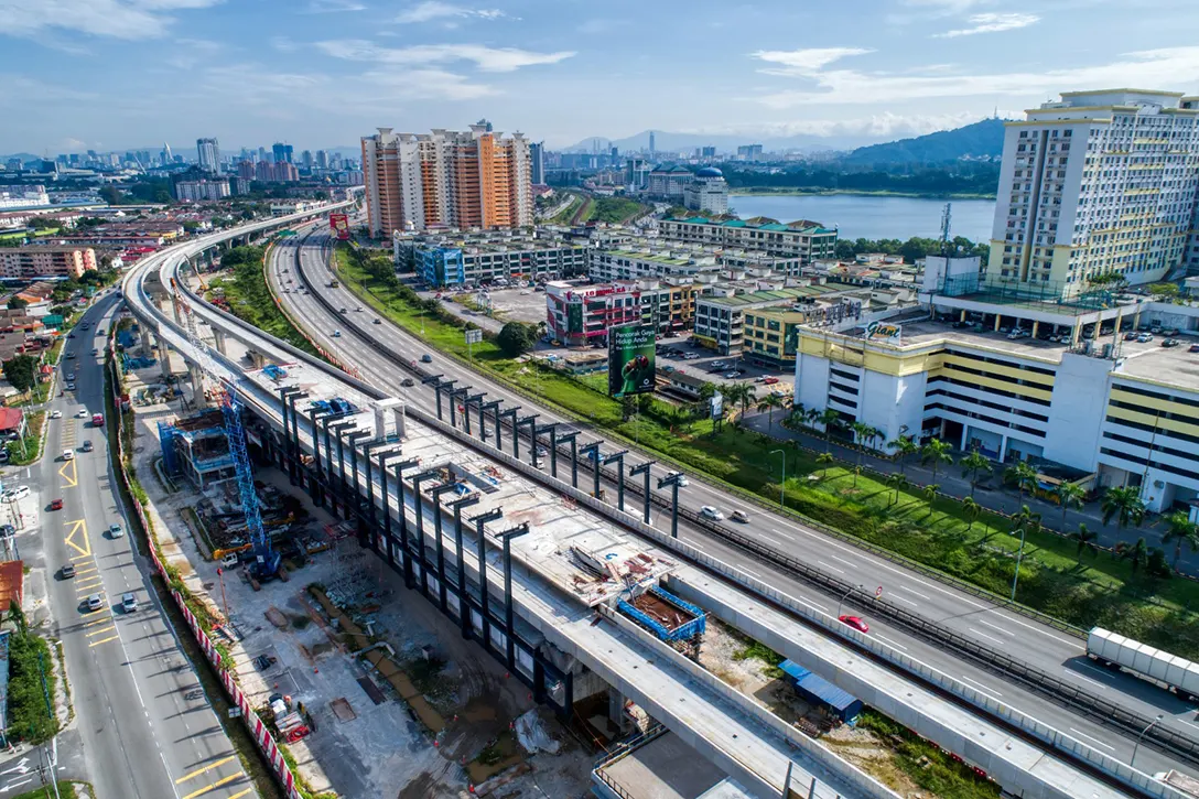 Aerial view of the Serdang Raya Selatan MRT Station site showing the steel column erection and roof truss preparation in progress.