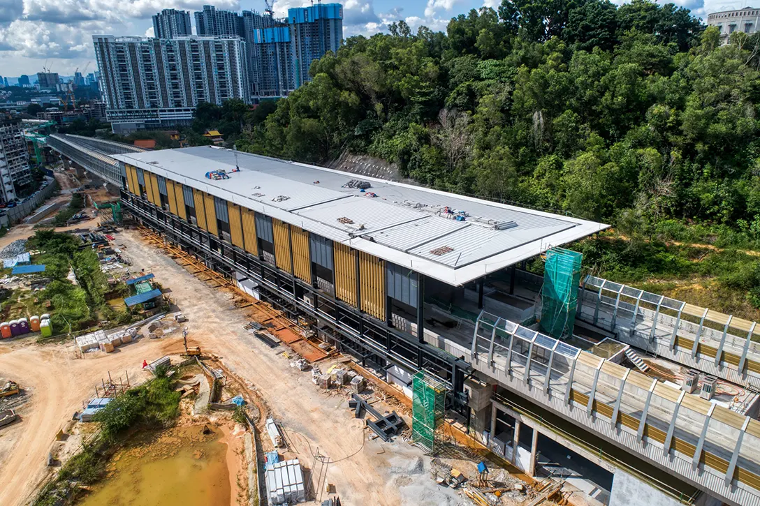 Aerial view of the Taman Naga Emas MRT Station site showing the installation of façade and roofing sheeting in progress.
